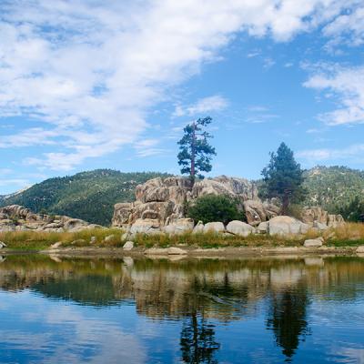 A landscape photo of a lake in front of mountains under a blue sky in Big Bear, CA.
